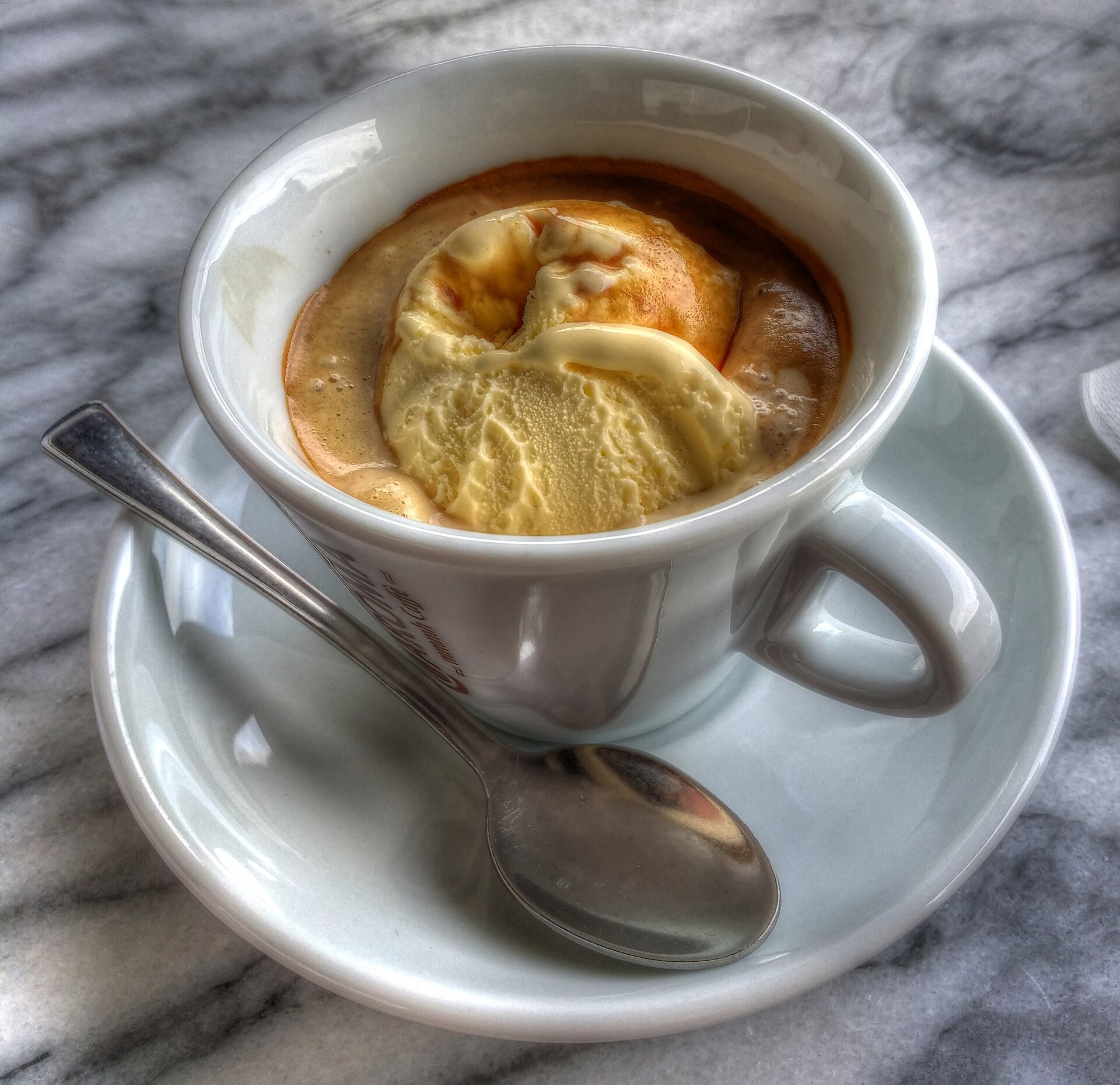 Finished vanilla affogato: espresso visibly surrounds the ice cream, unlike the earlier preparation-only reference.