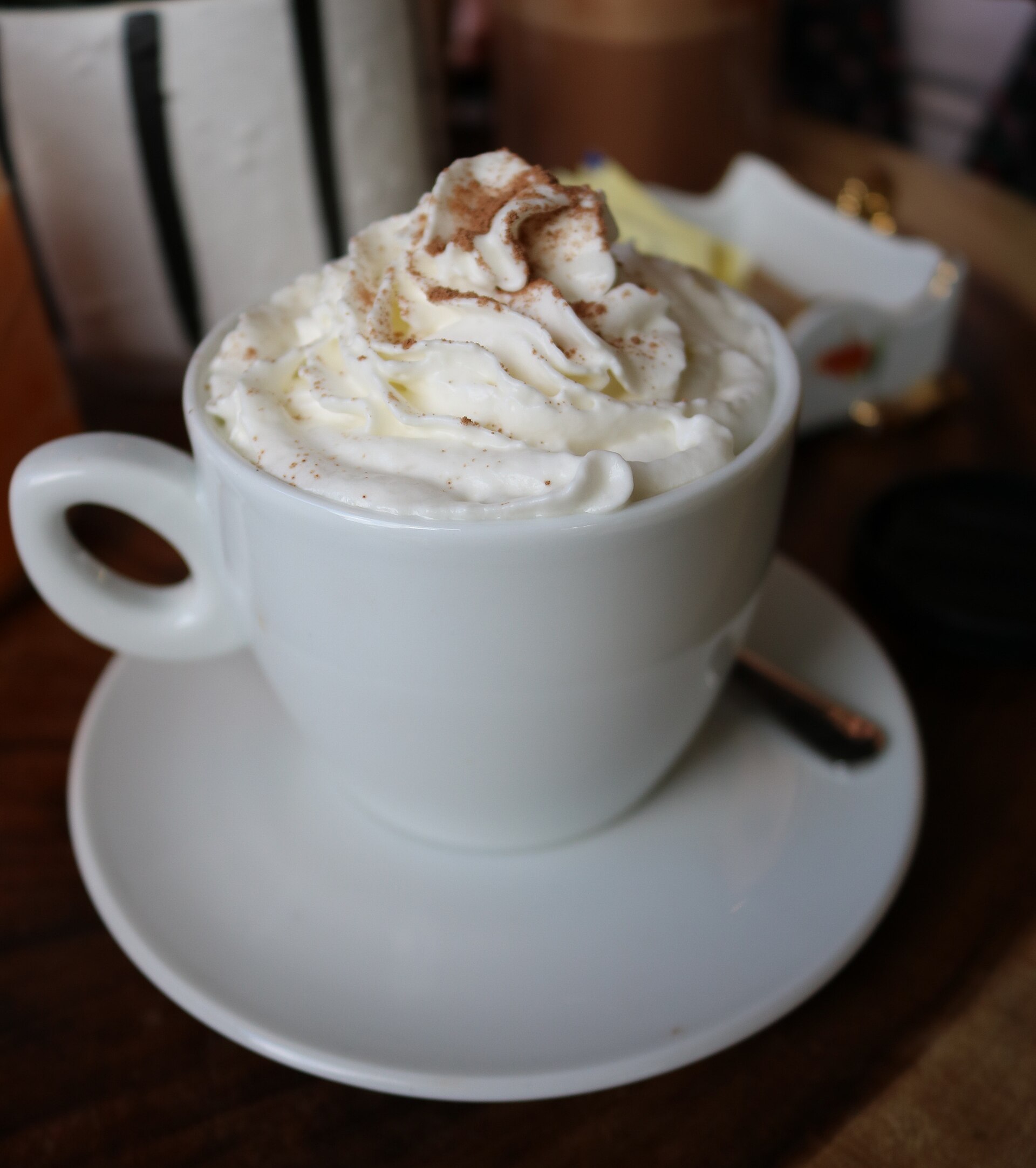 Source-identified espresso con panna with whipped cream and a dusted garnish. Coffee quantity is concealed; the garnish is photographic presentation only.