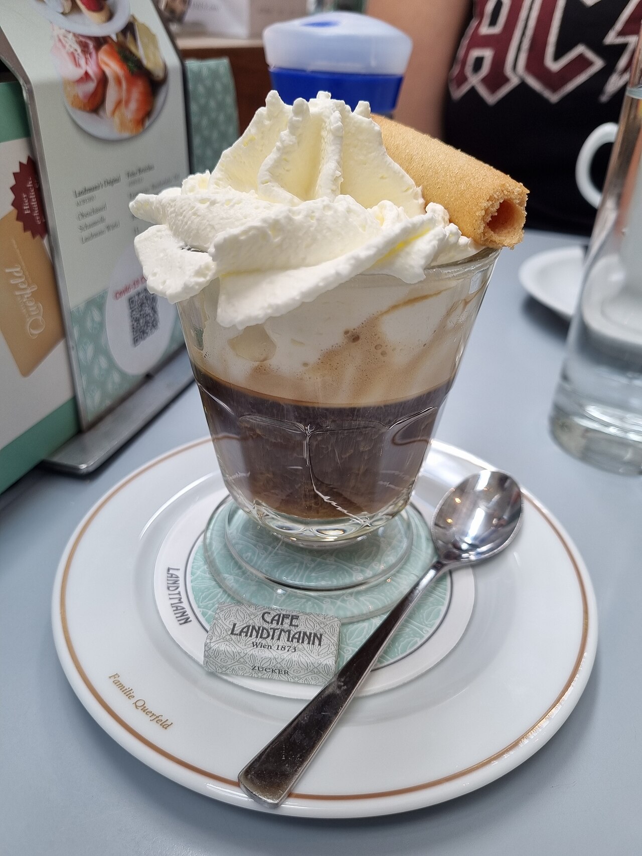 Source-identified Einspänner at Café Landtmann in Vienna, topped with cream and a wafer. This illustrates a venue presentation, not a standard topping weight.