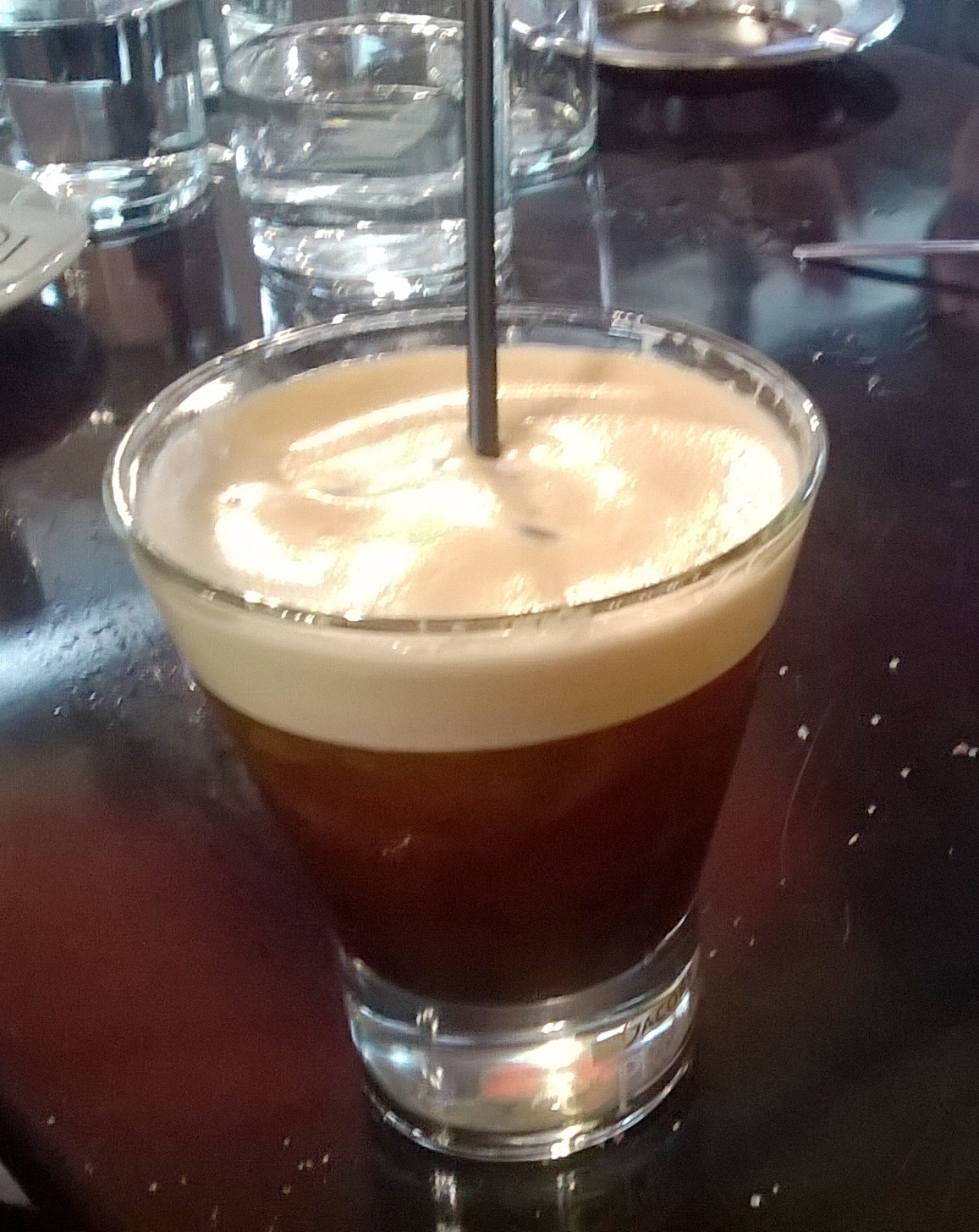 Source-identified freddo espresso. Its foamy surface comes from the coffee preparation; a milk topping belongs to freddo cappuccino.