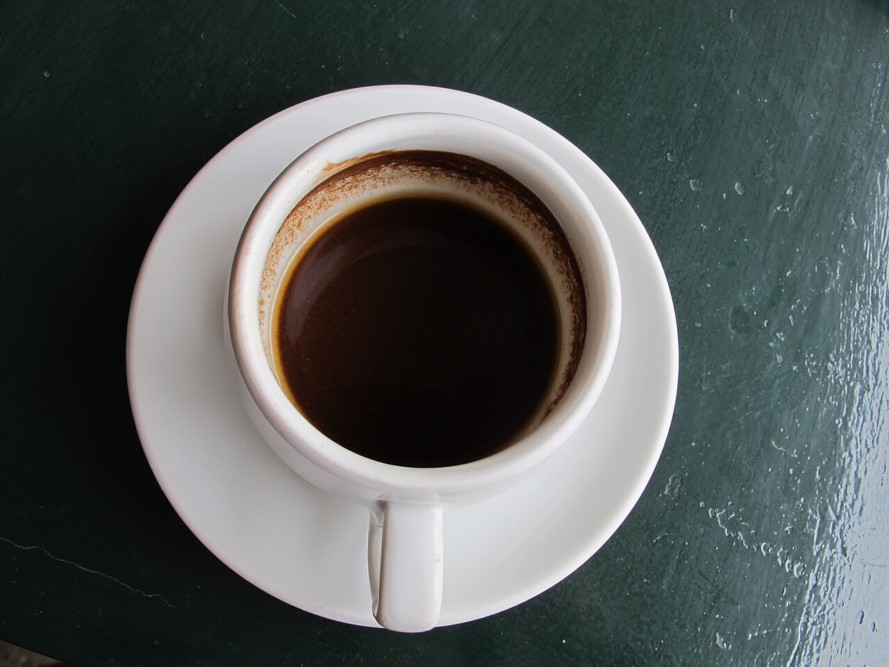 Source-identified Greek coffee photographed on Corfu. The image shows a real cup with a coffee residue ring, not proof of a particular grind, dose or sweetening level.