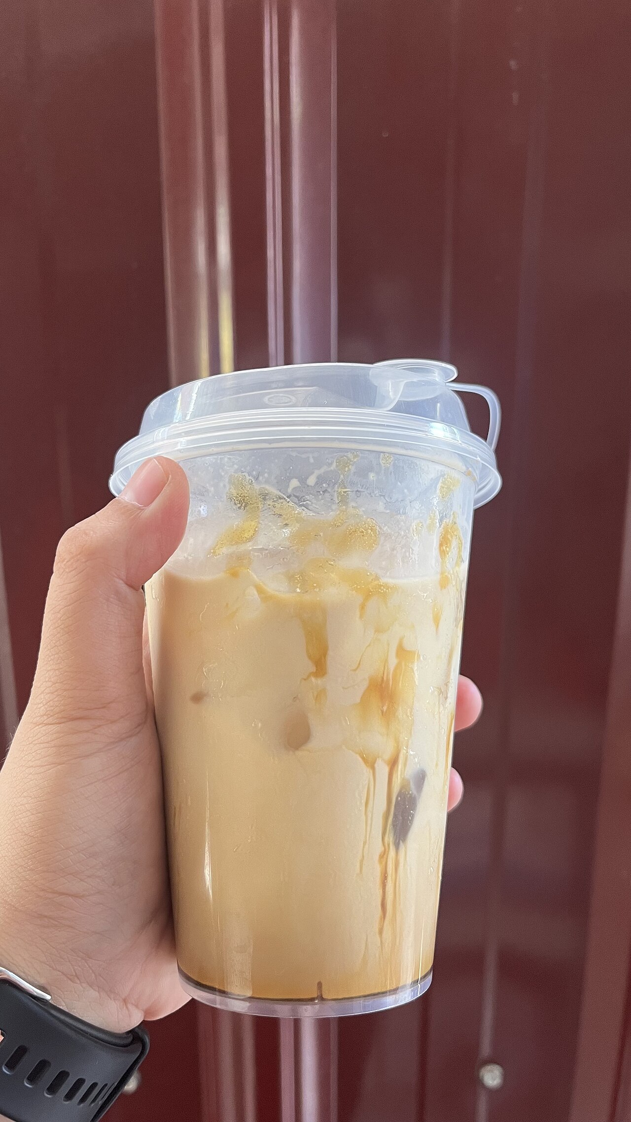 Real takeaway palm-sugar milk coffee. Serving vessel and syrup streaks differ from the named home assembly; the photograph is not a measurement of its inputs.