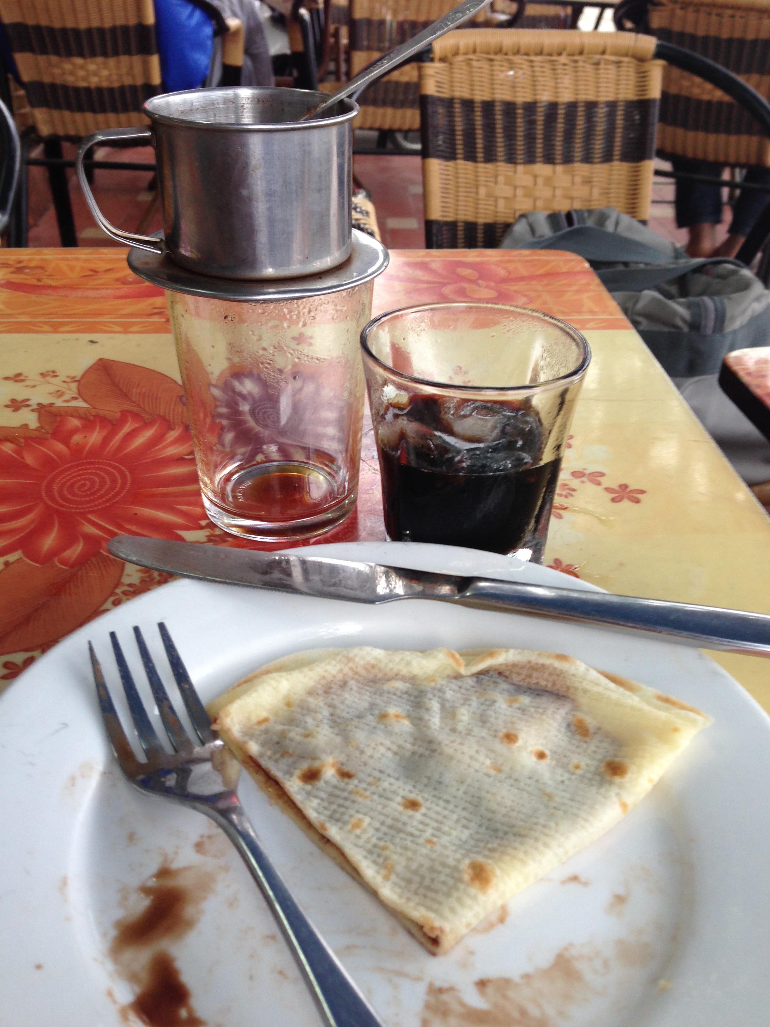 Smuconlaw photographed cà phê đá with a crêpe in Lào Cai in 2013. The finished iced drink is the right-hand glass; the phin at left shows separate preparation. Ingredient quantities are unknown.